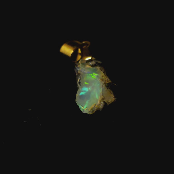 Video: raw uncut Ethiopian Welo opal pendant. Colour: blue and green, strong. Body: deep blue. Lying on a dark surface.