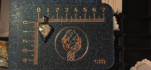 Raw uncut Ethiopian Welo opal pendant. Colour: red, green, vivid. Body: duotone blue/white. Placed next to a steel ruler for scale.
