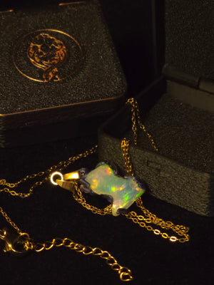 Raw uncut Ethiopian Welo opal pendant, every colour at once, blue body. Shown with its open gift box.