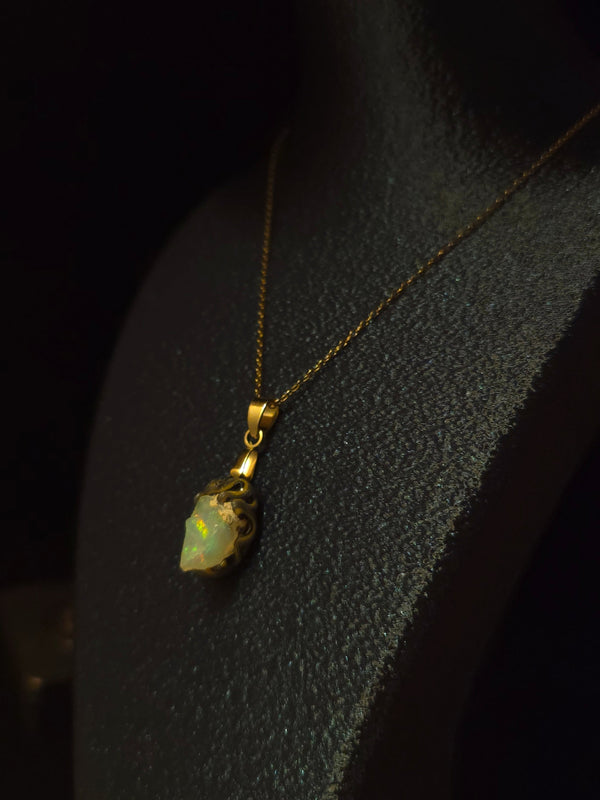 Raw uncut Ethiopian Welo opal pendant. Colour: green and red, strong. Body: light blue. Worn on a black display bust.