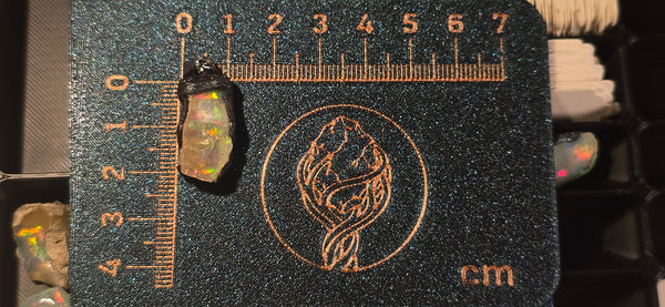 Raw uncut Ethiopian Welo opal pendant. Colour: multicolour, vivid. Body: light, deeper than usual. Placed next to a steel ruler for scale.