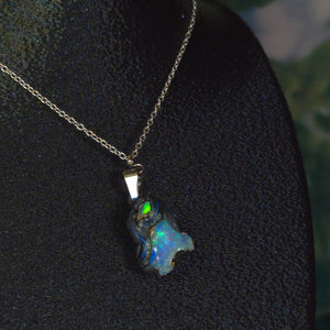 Raw uncut Ethiopian Welo opal pendant. Colour: green, blue, vivid. Body: blue. Worn on a black display bust.