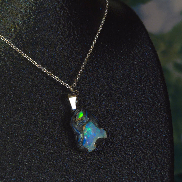 Raw uncut Ethiopian Welo opal pendant. Colour: green, blue, vivid. Body: blue. Worn on a black display bust.