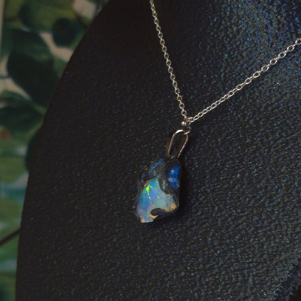 Raw uncut Ethiopian Welo opal pendant. Colour: green, blue, vivid. Body: blue. Worn on a black display bust.