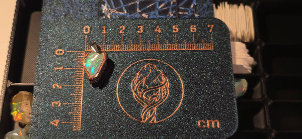 Raw uncut Ethiopian Welo opal pendant. Colour: blue, green, yellow, red, full spectrum, vivid. Body: clear. Placed next to a steel ruler for scale.