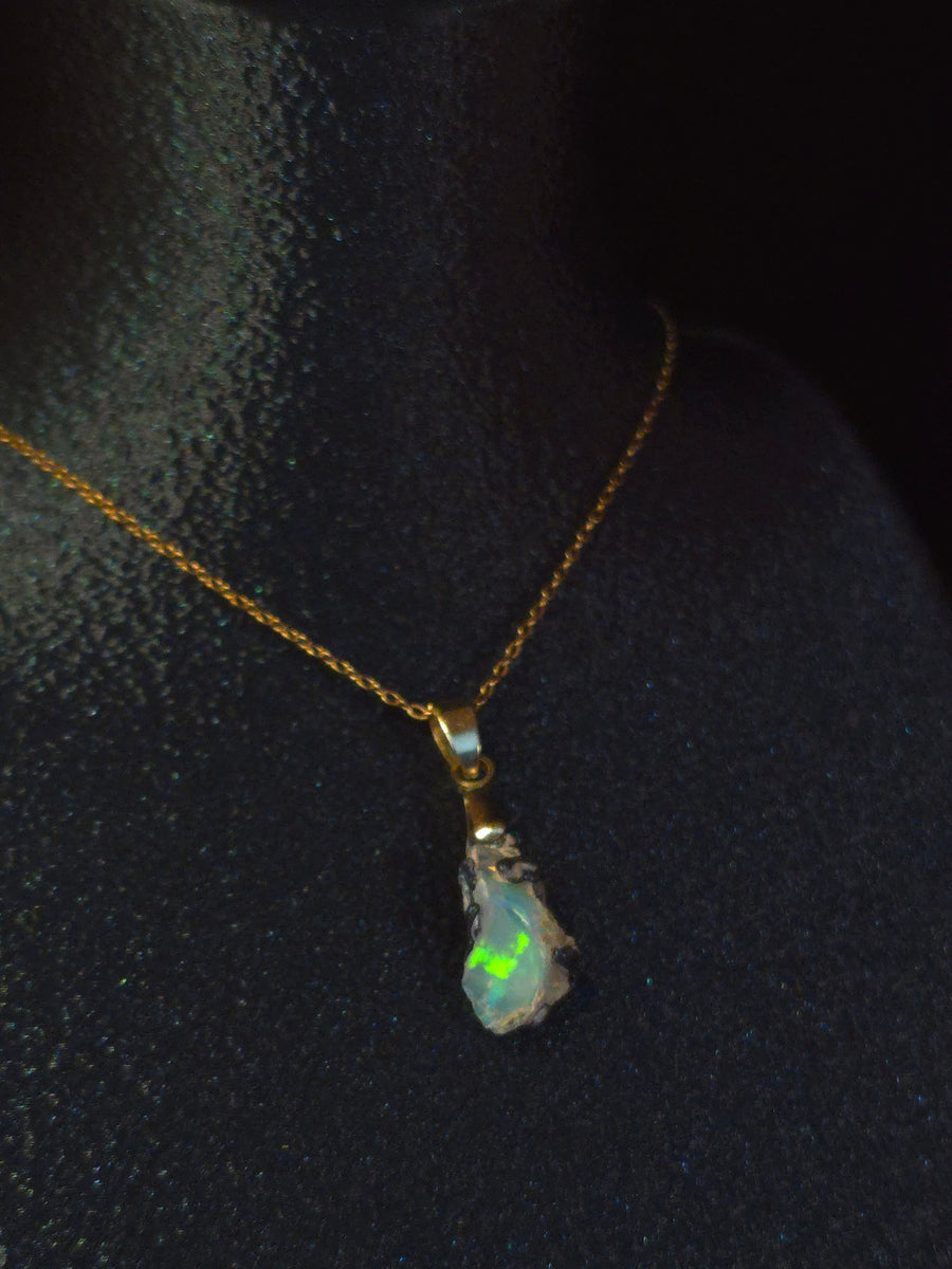 Raw uncut Ethiopian Welo opal pendant. Colour: blue and green, strong. Body: deep blue. Worn on a black display bust.