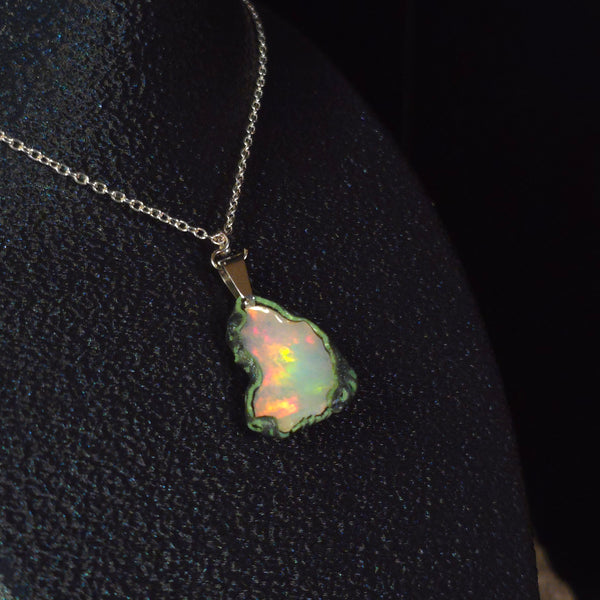 Raw uncut Ethiopian Welo opal pendant. Colour: full spectrum rainbow, moderate. Body: white. Worn on a black display bust.