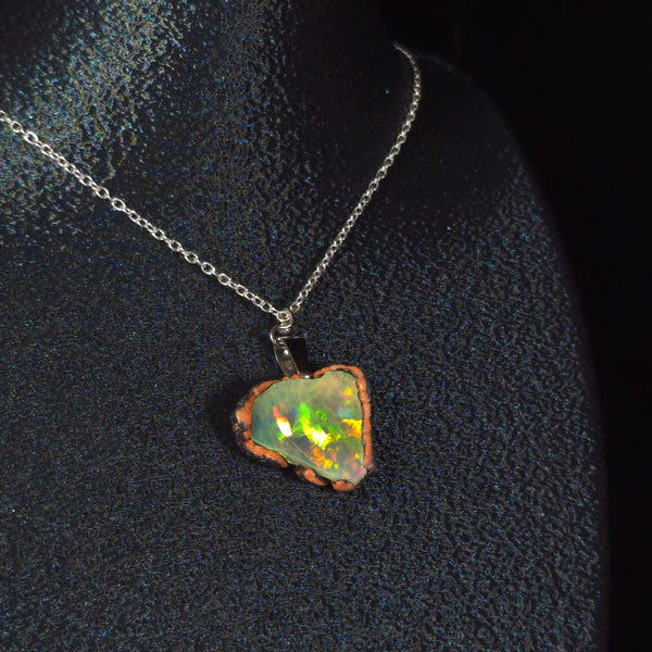 Raw uncut Ethiopian Welo opal pendant. Colour: full rainbow, vivid. Body: dark. Worn on a black display bust.