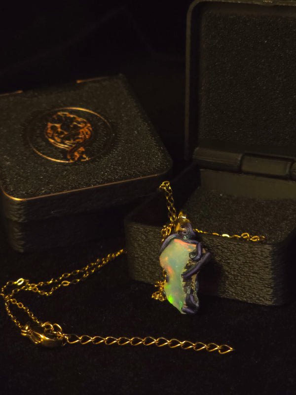 Raw uncut Ethiopian Welo opal pendant, every colour at once, blue body. Shown with its open gift box.