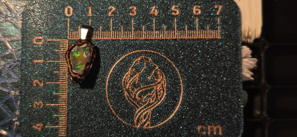 Raw uncut Ethiopian Welo opal pendant. Colour: red and green with blue at the edges, bold. Body: warm golden. Placed next to a steel ruler for scale.