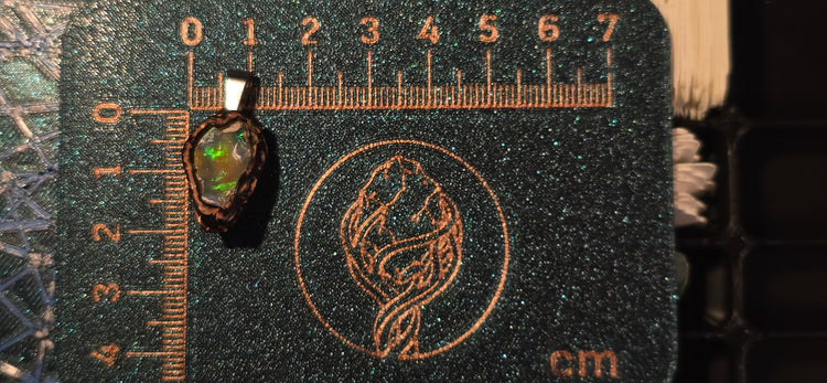 Raw uncut Ethiopian Welo opal pendant. Colour: red and green with blue at the edges, bold. Body: warm golden. Placed next to a steel ruler for scale.