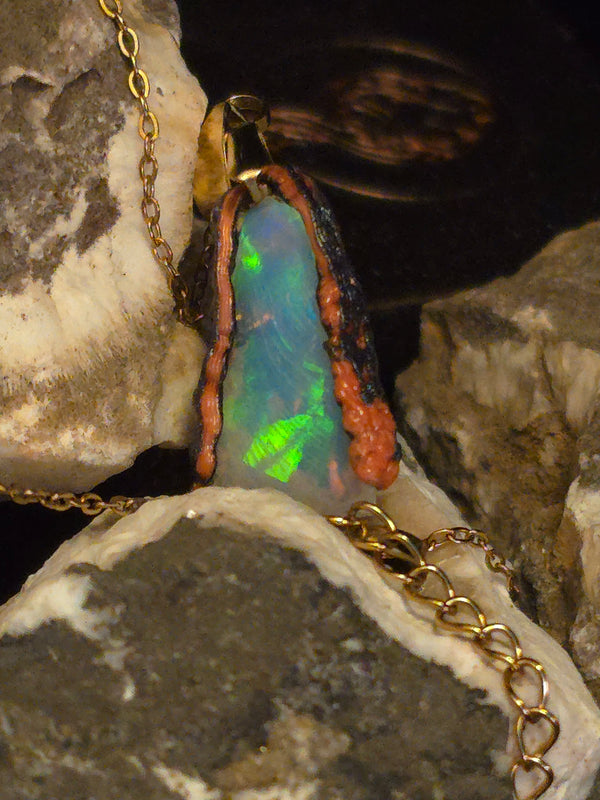 Raw uncut Ethiopian Welo opal pendant. Colour: green leading, red cutting in, blue at the edges, strong. Body: crystal clear. Resting on rough rock.