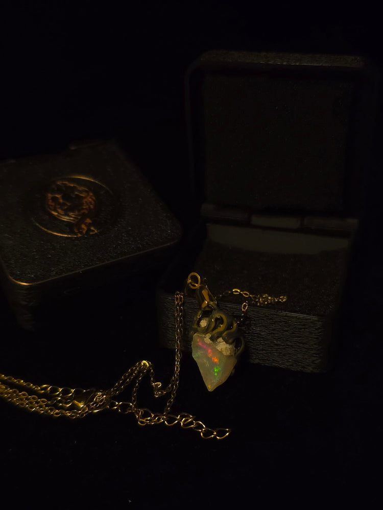 Raw uncut Ethiopian Welo opal pendant. Colour: green and red, strong. Body: light blue. Shown with its open gift box.