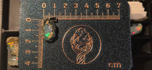 Raw uncut Ethiopian Welo opal pendant. Colour: green and blue, strong. Body: clear, light blue. Placed next to a steel ruler for scale.