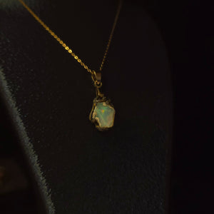 Raw uncut Ethiopian Welo opal pendant. Colour: green and red, strong. Body: light blue. Worn on a black display bust.