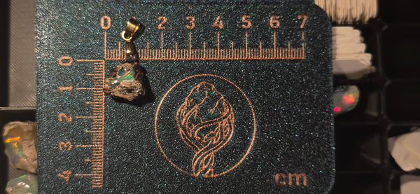 Raw uncut Ethiopian Welo opal pendant. Colour: red, green, vivid. Body: deep blue, volcanic matrix. Placed next to a steel ruler for scale.