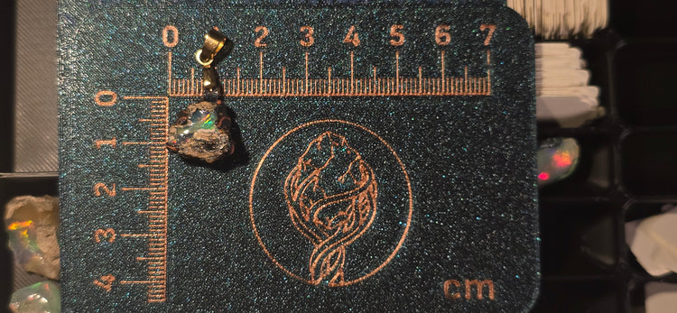 Raw uncut Ethiopian Welo opal pendant. Colour: red, green, vivid. Body: deep blue, volcanic matrix. Placed next to a steel ruler for scale.