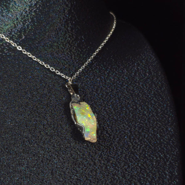 Raw uncut Ethiopian Welo opal pendant. Colour: blue and green, vivid. Body: transparent. Worn on a black display bust.